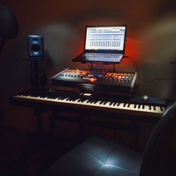 Small Bedroom Recording Studio Interior of a small bedroom recording studio, details of equipment, microphone in foreground and modern mixing console with laptop in background.